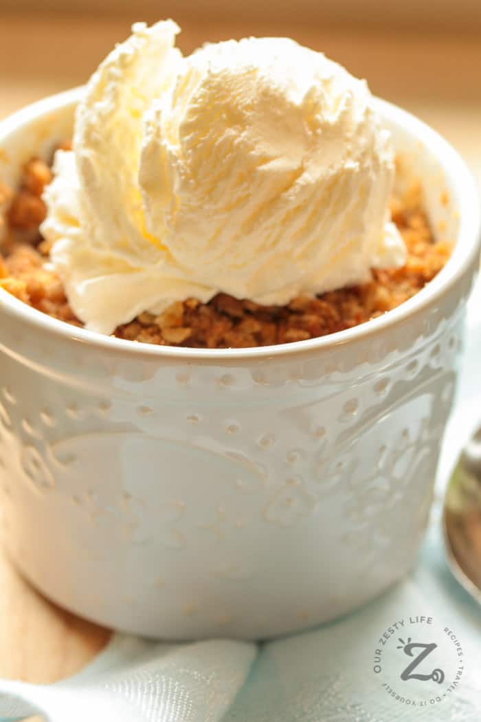 Individual Easy Peach Crisp with ice cream and a light blue napkin in the background