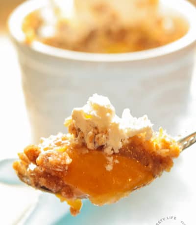 Easy Peach Crisp Recipe with peach crisp and ice cream on a spoon with an individual easy peach crisp in the background