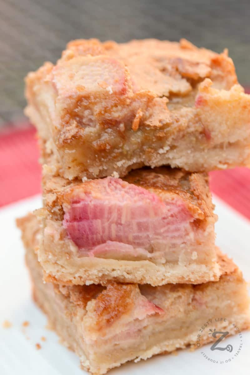 Closeup of a stack of three shortbread rhubarb bars on a white plate