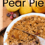 Cranberry Pear Pie in a white pie plate being cut into slices, with pears and cranberries in the background