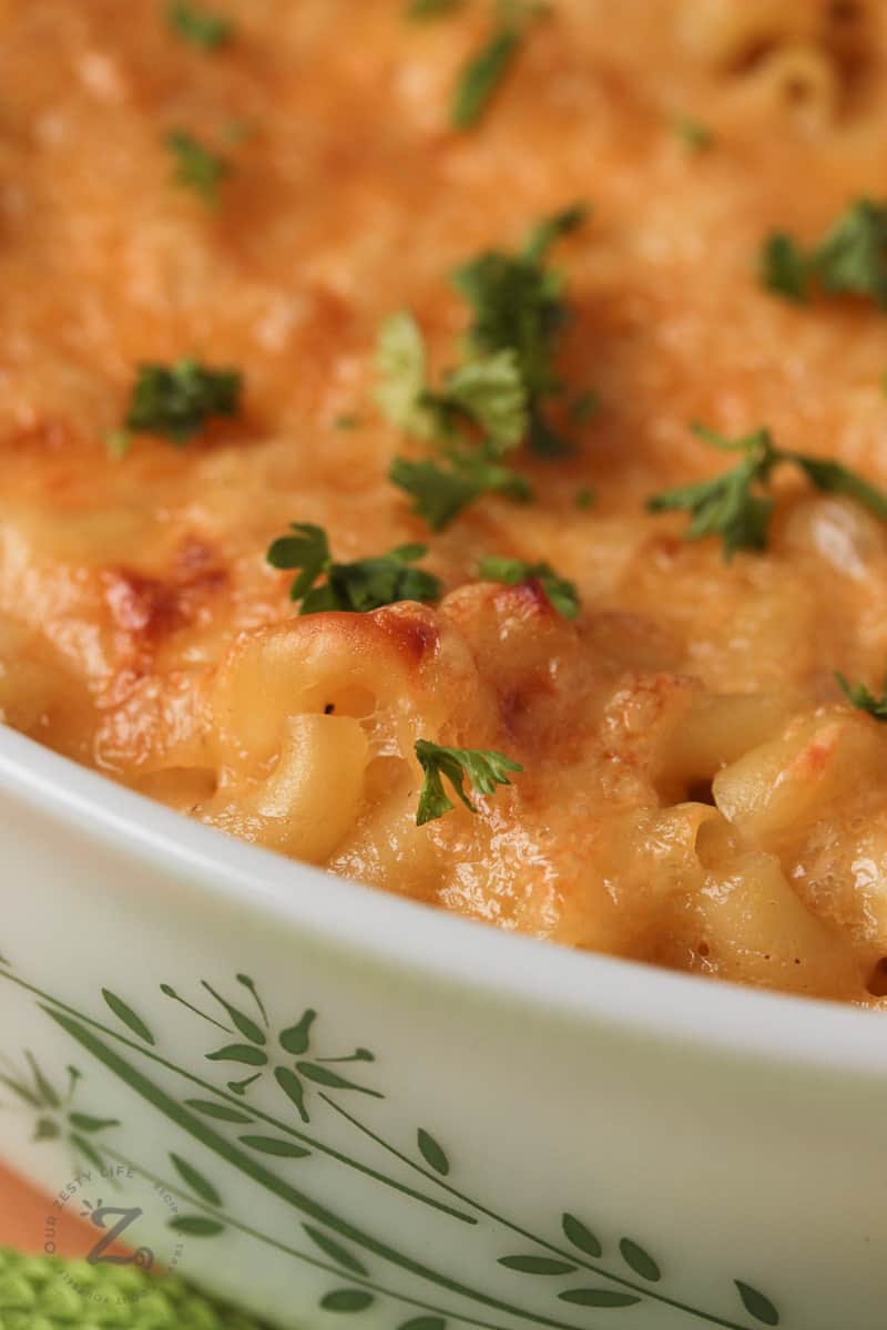 closeup of homemade baked macaroni and cheese in a white casserole dish garnished with parsley