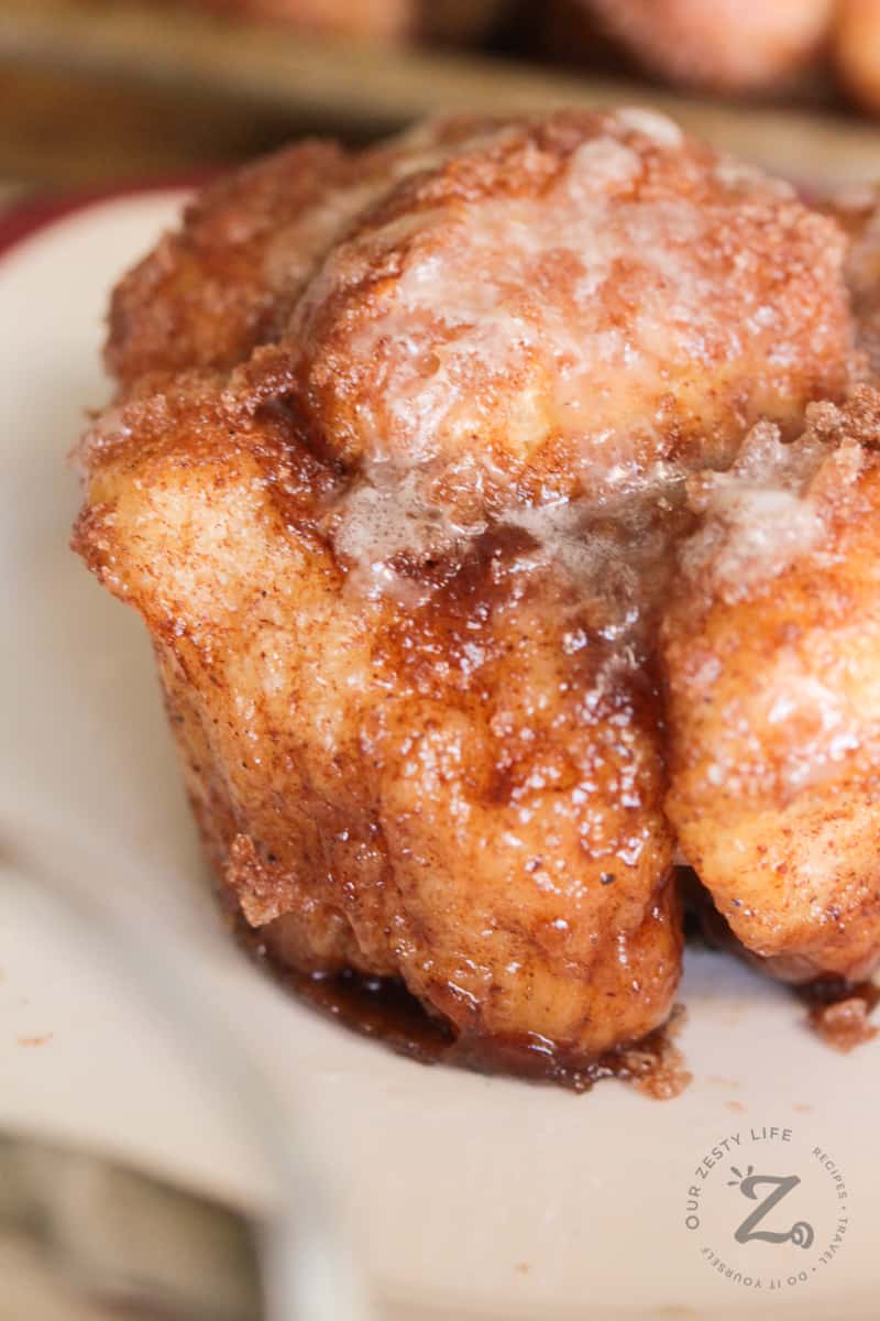 closeup of cinnamon monkey bread muffins with vanilla glaze on a white plate