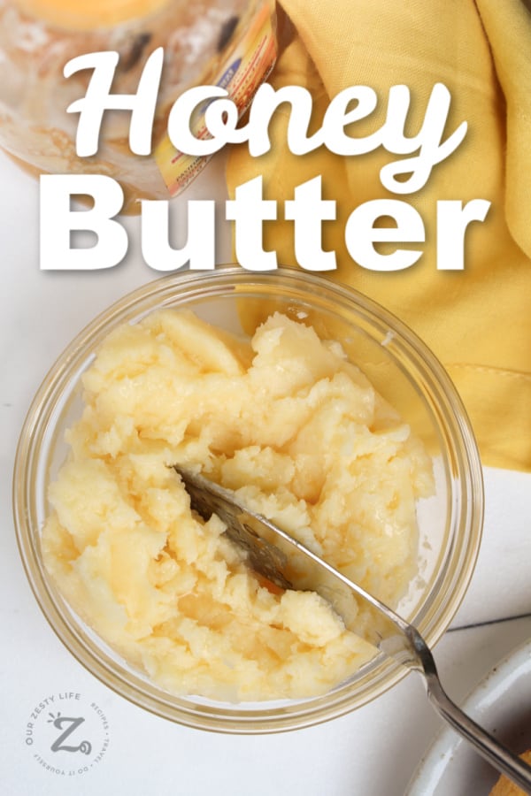 honey butter being in a glass bowl with a butter knife with a honey jar and yellow napkin in the background