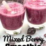 Overhead of two glasses of mixed berry smoothie with straws and berries in the on the table and a bag of frozen berries in the background