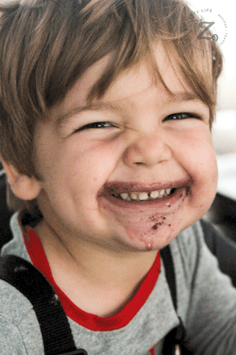 boy with a huge smile with mixed berry smoothie on his face