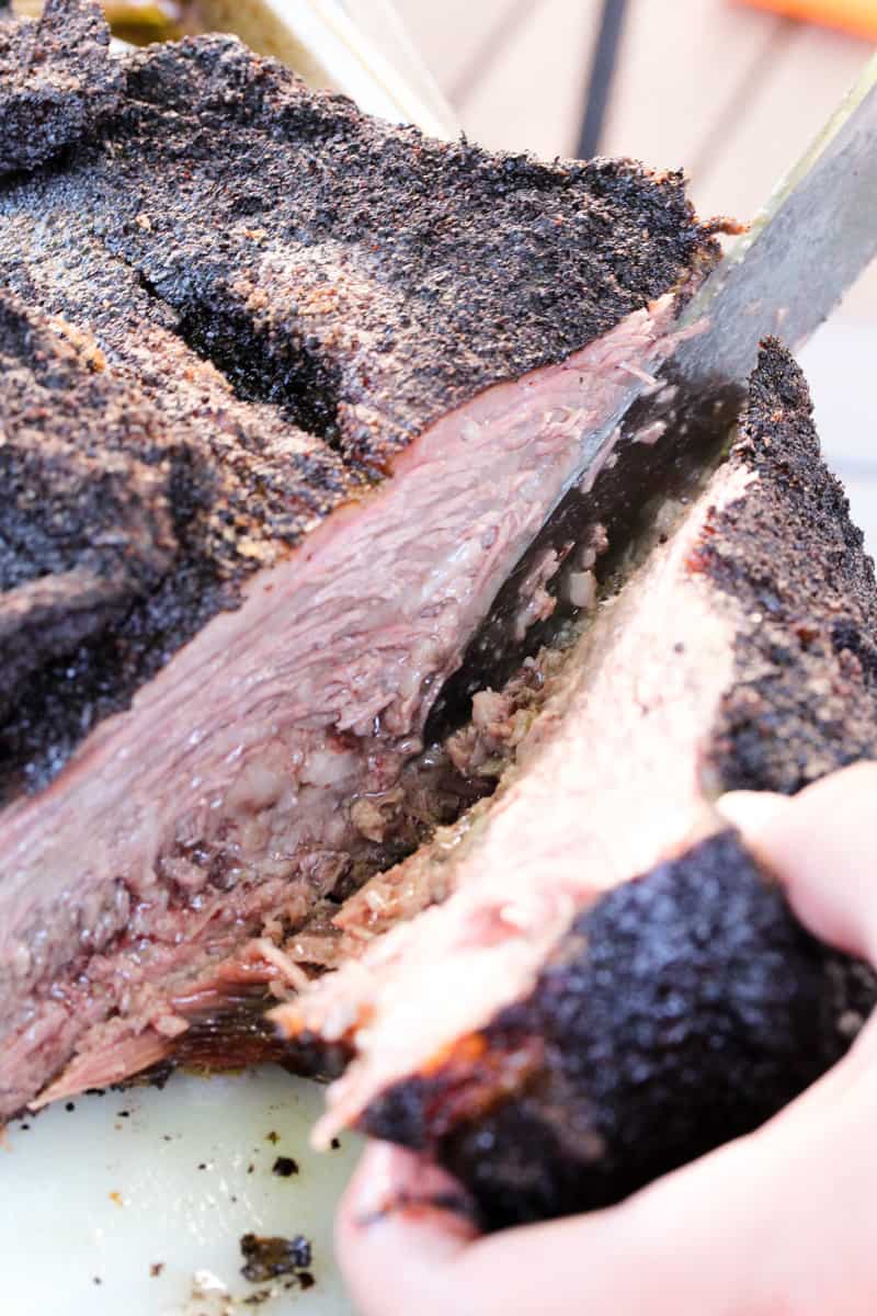 smoked beef brisket being cut with a knife