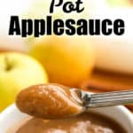 Instant Pot applesauce in a small white bowl with apples in the background and a spoon holding some applesauce in the foreground