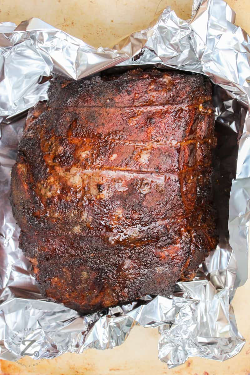 The Boston butt pork shoulder, pulled pork cooked roast before it is resealed in aluminum foil and placed back in the smoker