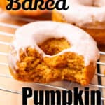 Glazed Pumpkin Spice Donuts on a baking tray with a bite of it and pumpkins on the side
