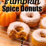 Glazed Pumpkin Spice Donuts on a baking tray and pumpkins on the side