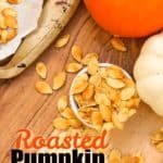 Roasted Pumpkin Seeds in a bowl with pumpkins and a baking tray on the side