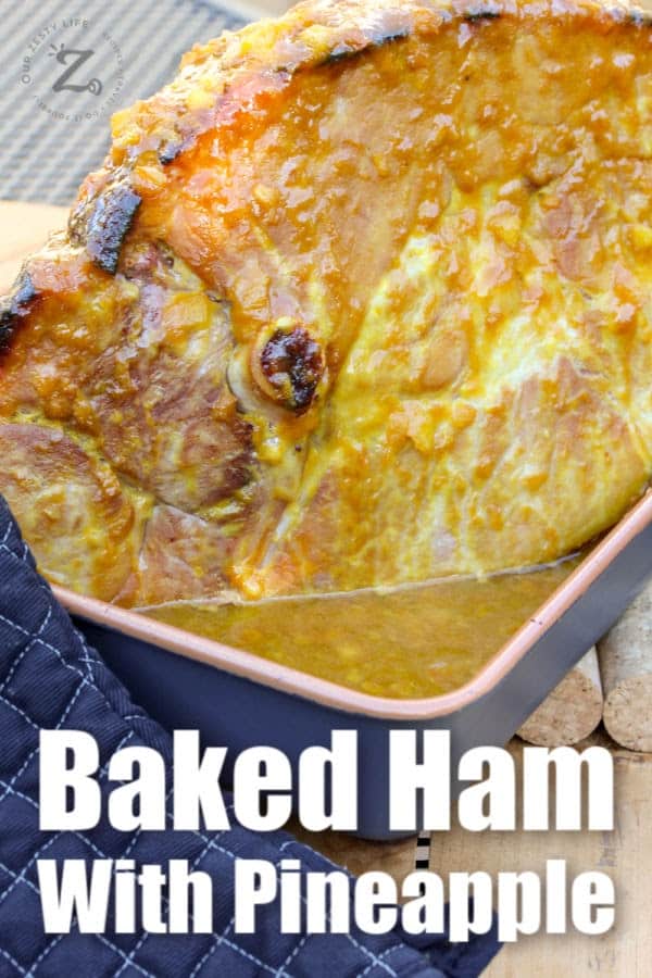 oven baked ham with pineapple mustard glaze in a roasting pan, with an oven mitt on the side