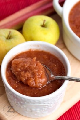 Instant Pot Rhubarb Applesauce in a white dish with a spoon with apples in the background