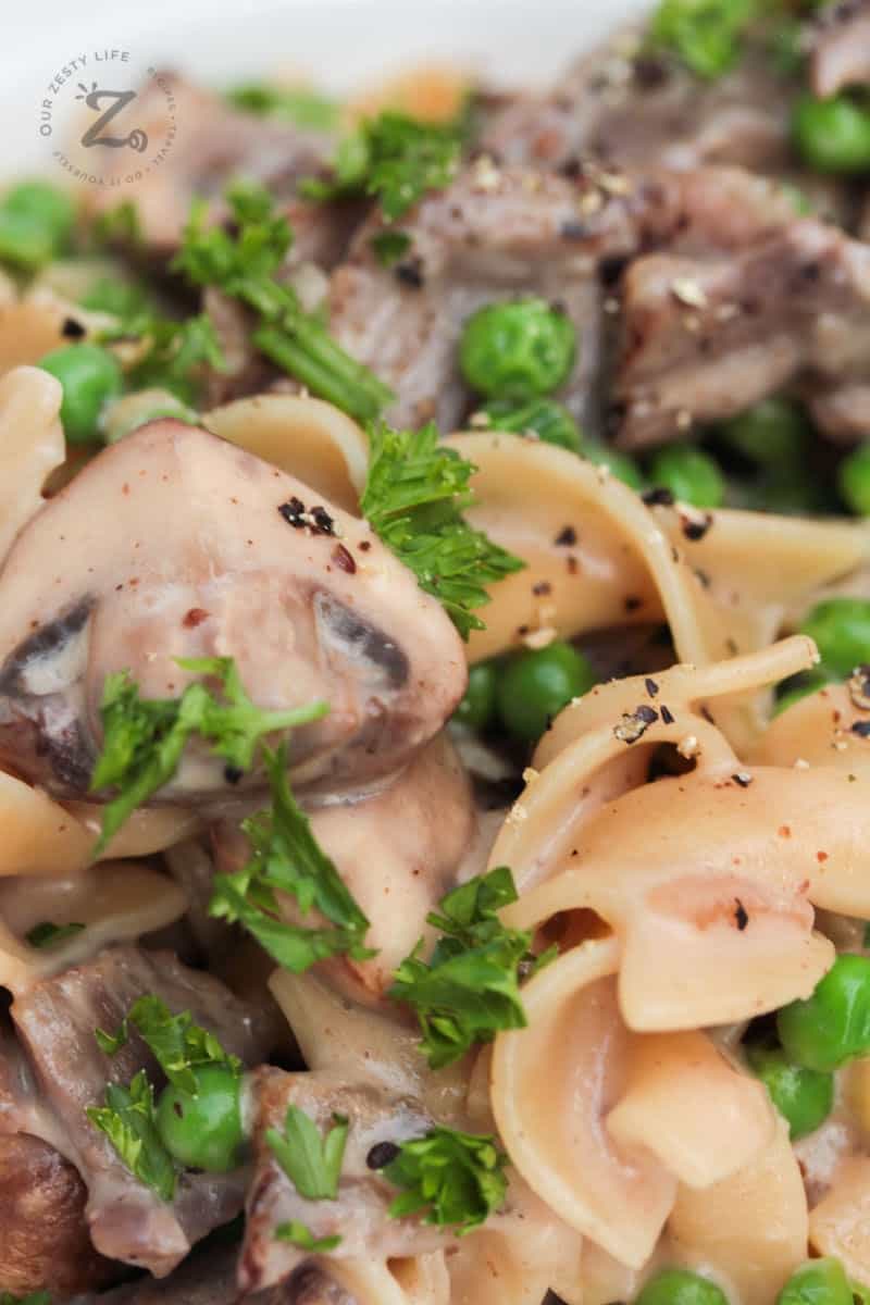 Close up of beef stroganoff with egg noodle, mushrooms and peas