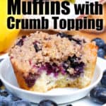 a Blueberry Muffin with Crumb Topping on a white plate with blueberries and muffins on the side