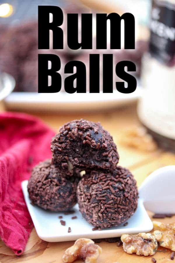 Three chocolate rum balls with chocolate sprinkles on a small white plate