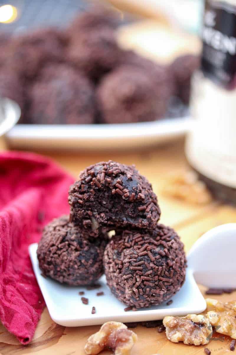 Three chocolate rum balls with chocolate sprinkles on small white plate