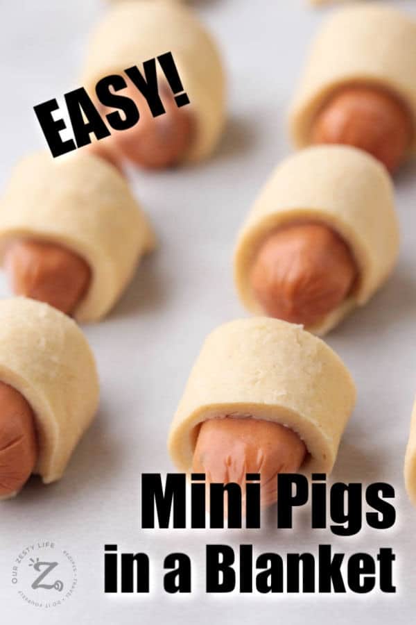 picture close up of 6 unbaked mini pigs in a blanket on a cooking sheet