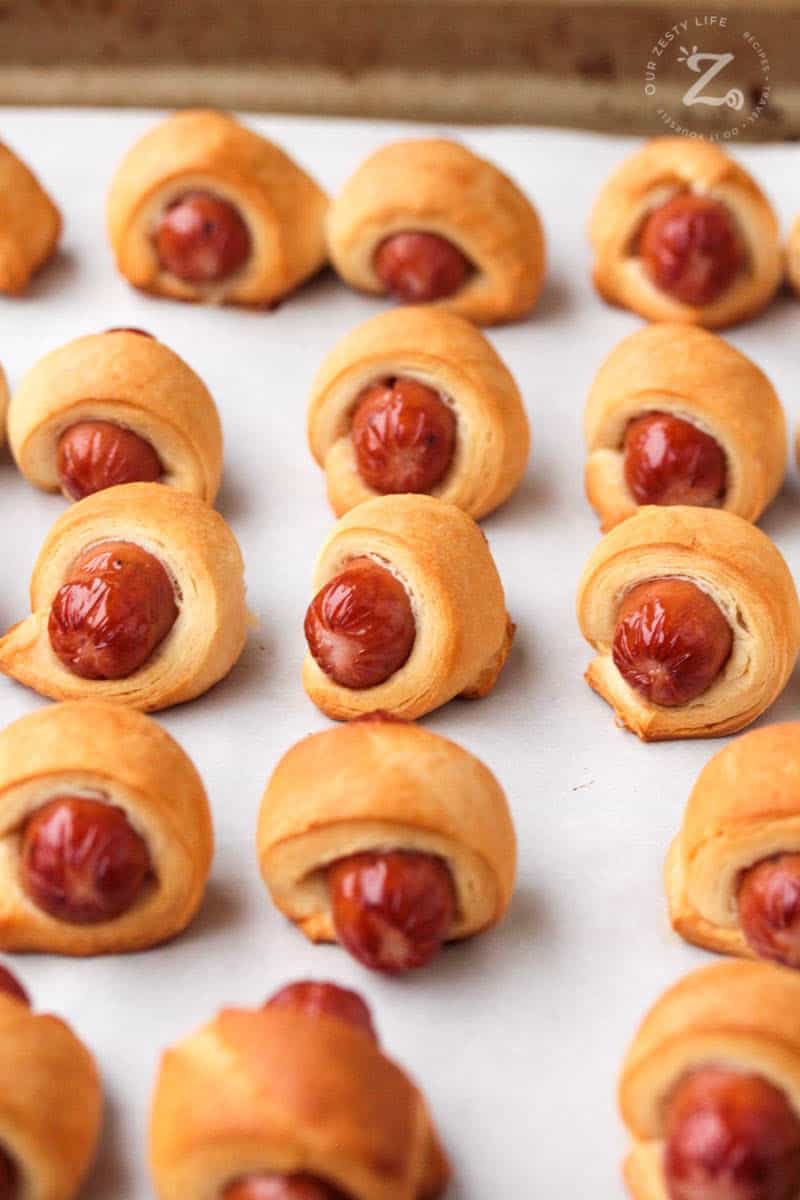 picture close up of 16 baked mini pigs in a blanket on a cooking sheet
