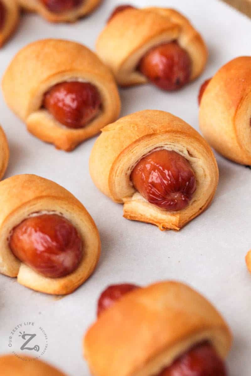 picture close up of 6 baked mini pigs in a blanket on a cooking sheet