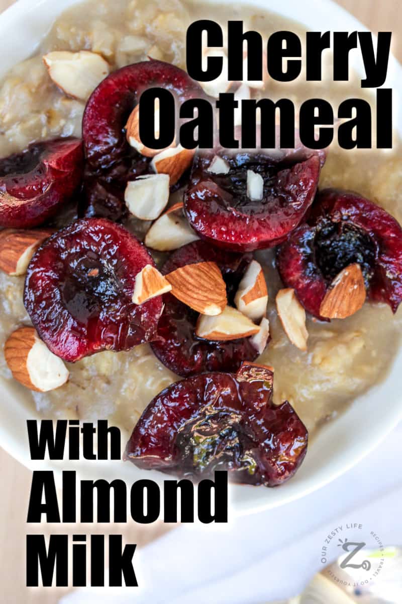 overhead view of pitted cherries sliced in half on top of oatmeal and almond milk in a bowl
