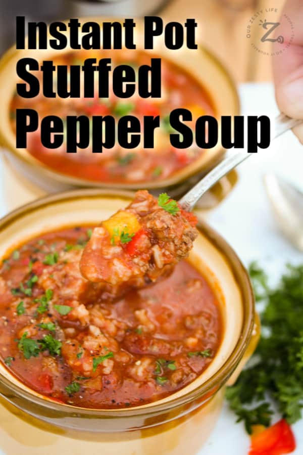 A close up of a spoonful of Instant Pot stuffed pepper soup held over top of a bowl f stuffed pepper soup and another bowl in the background.