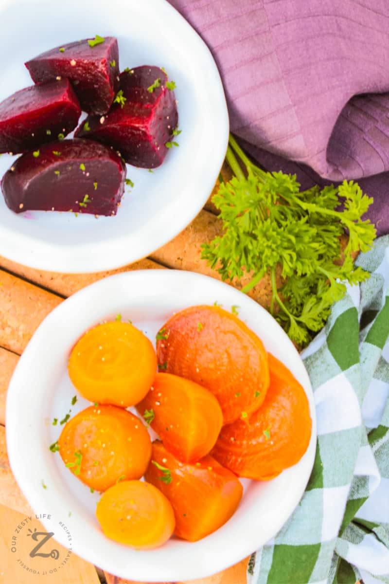 a close up of yellow beets on a white plate and a plate of red beets in the background