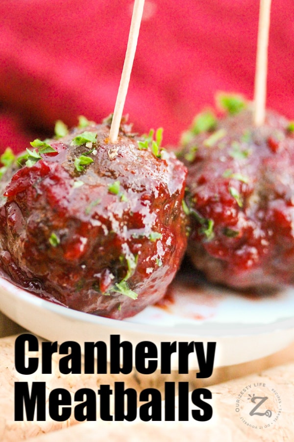 a close up of two cranberry meatballs with a toothpick in each on a small plate