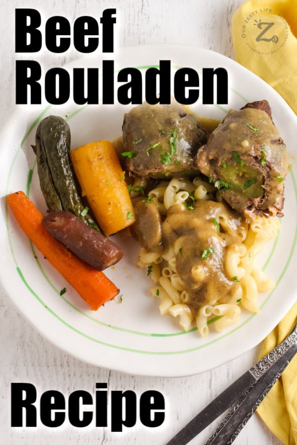 A serving of Beef rouladen with carrots, pickles, and macaroni with writing.