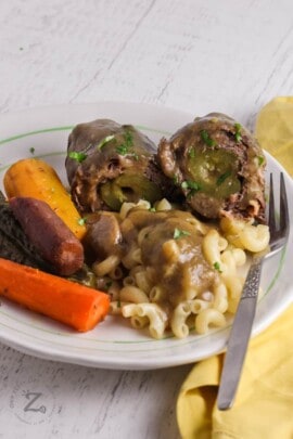 A serving of beef rouladen with macaroni and rainbow carrots