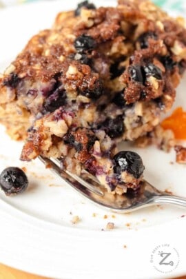 Blueberry banana baked oatmeal on a white plate with a bite on a fork