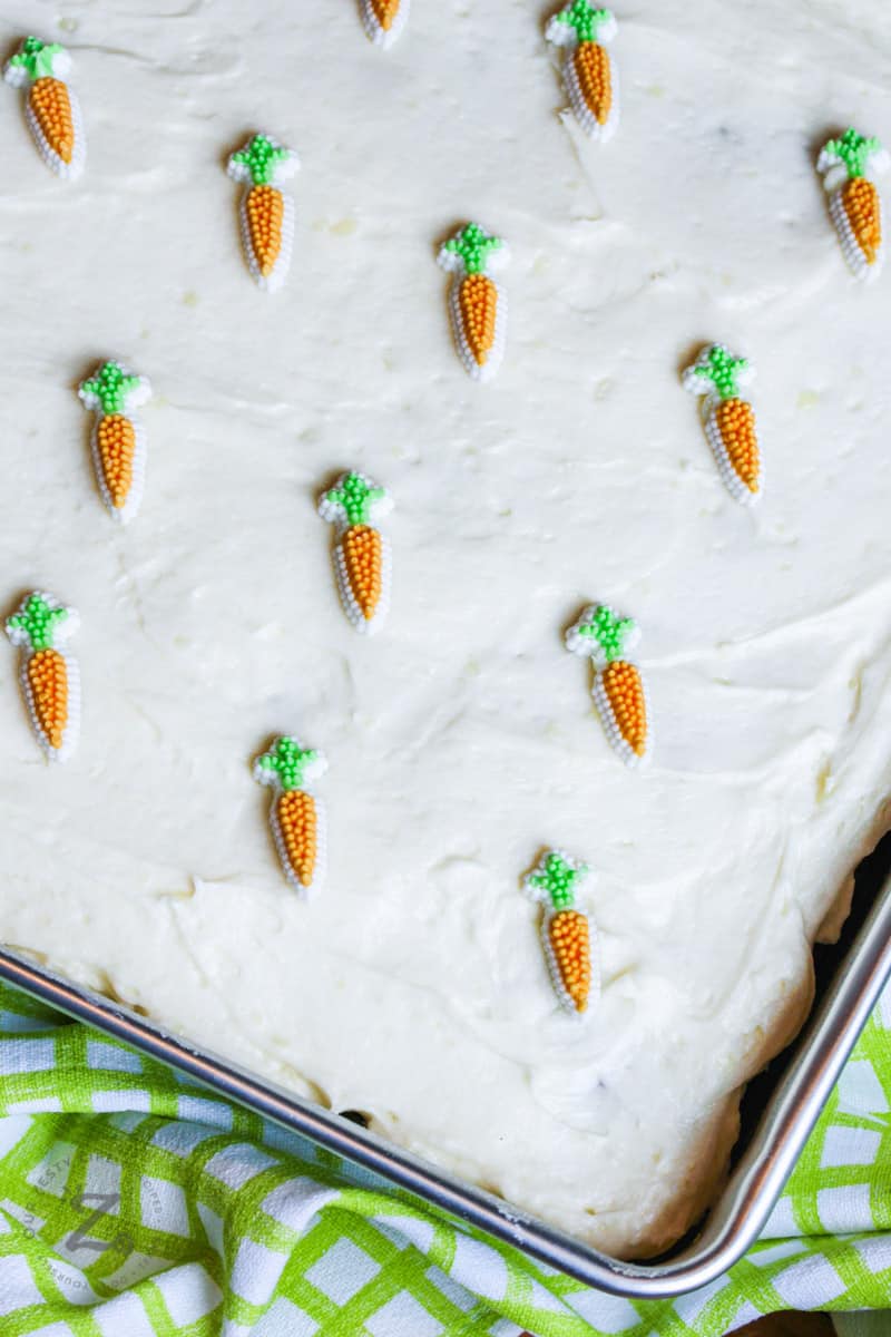 Homemade carrot cake in a pan with icing and candy carrots 