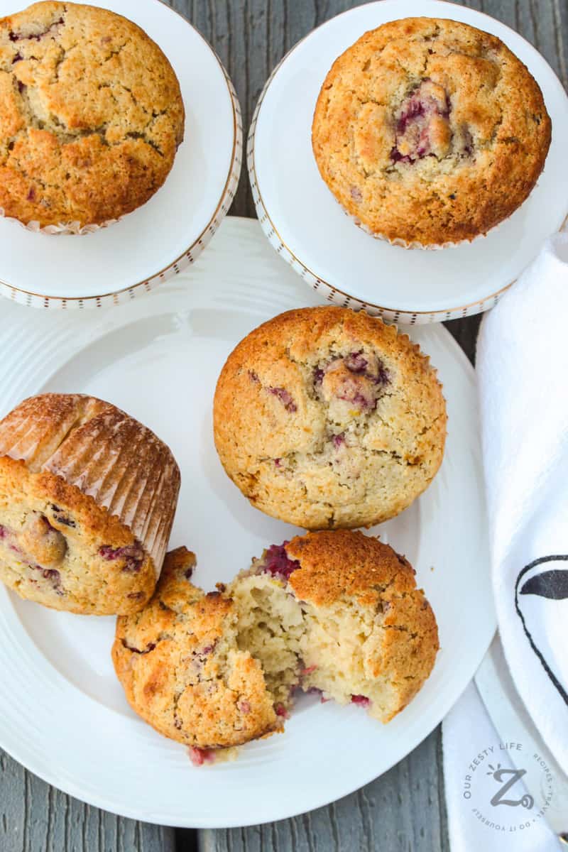 Raspberry Muffins on serving plates with one muffin broken in half to show inside