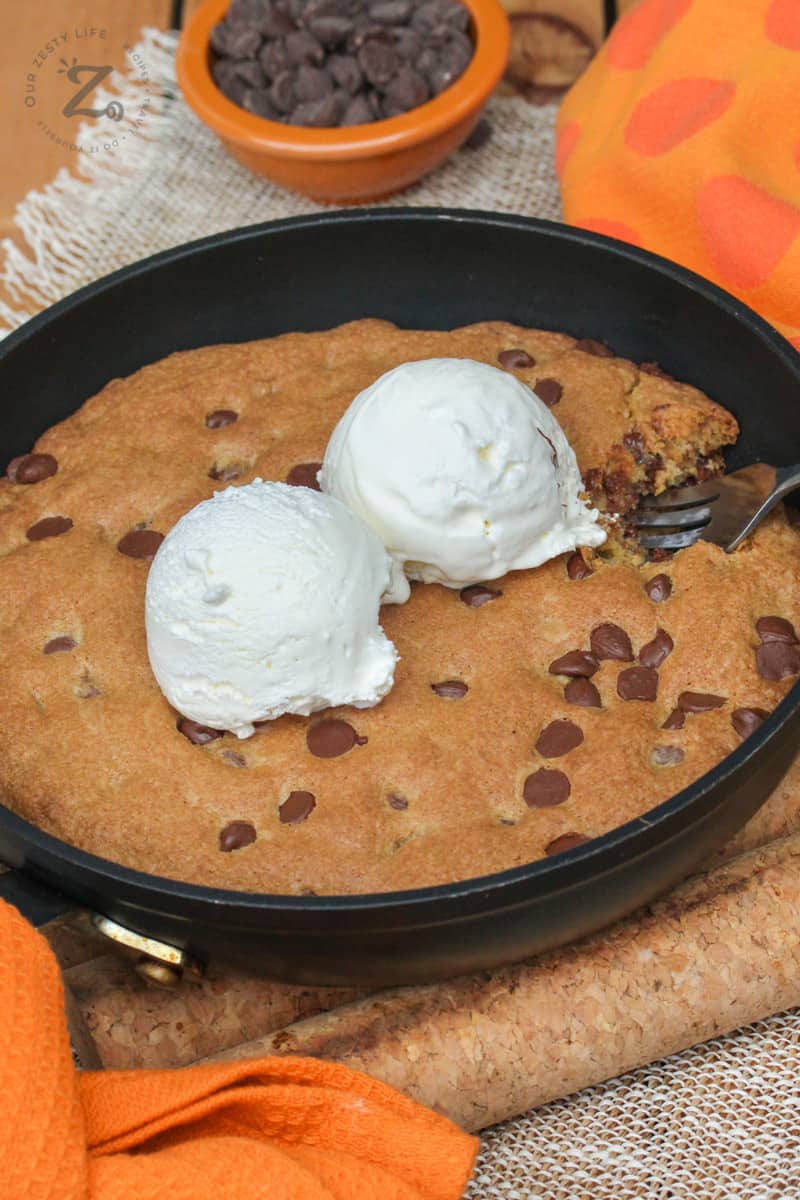 Pizookie in a pan with a fork and two scoops of ice cream