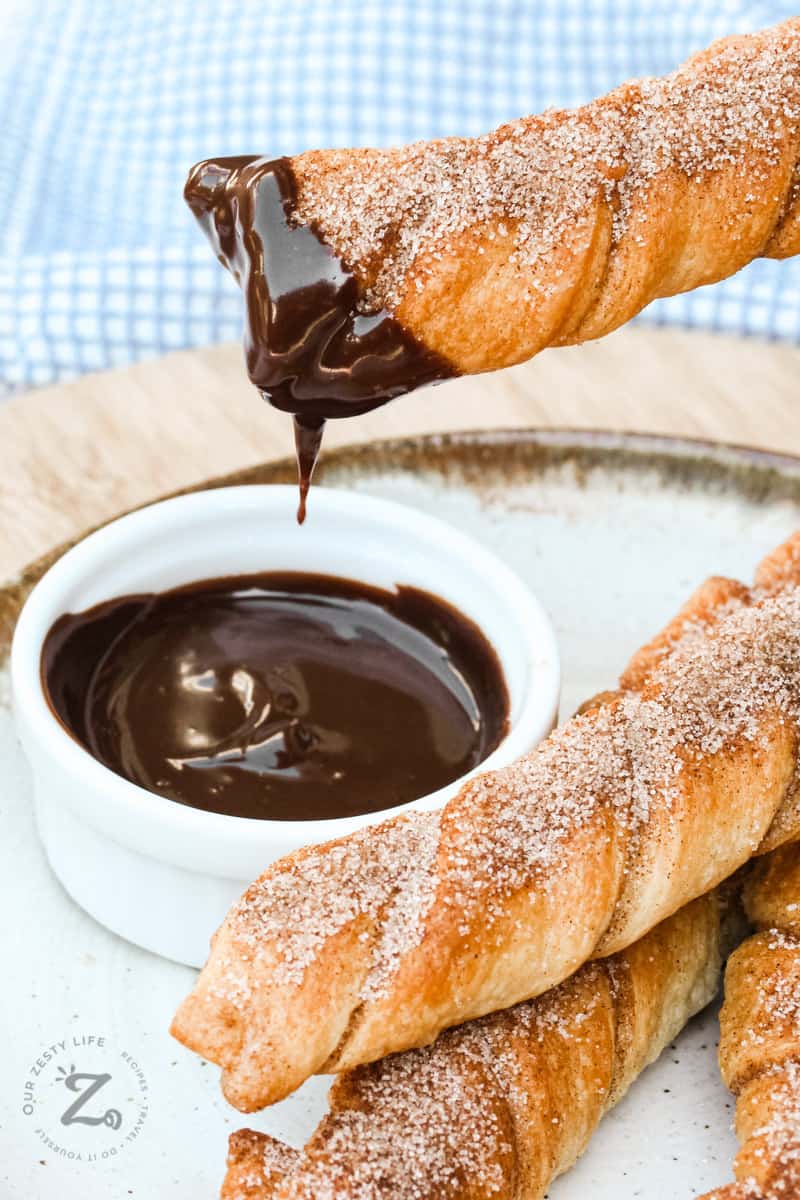 Baked Churros being dipped with chocolate sauce