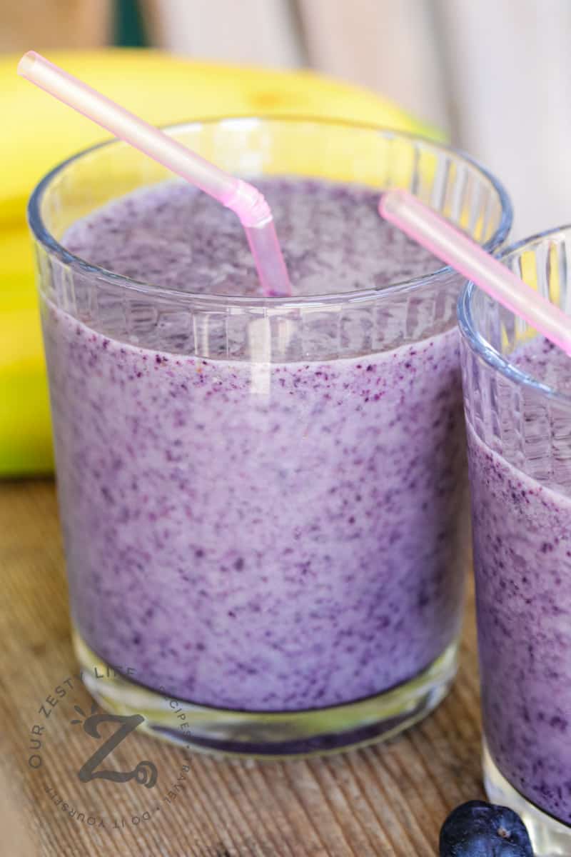 Blueberry Banana Smoothies in two clear glasses with straws
