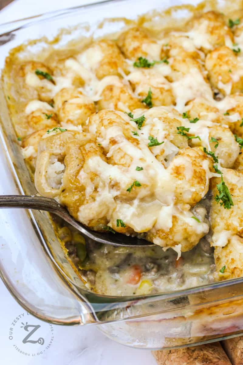 baked Cheesy Tater Tot Casserole with a metal spoonful getting taken out