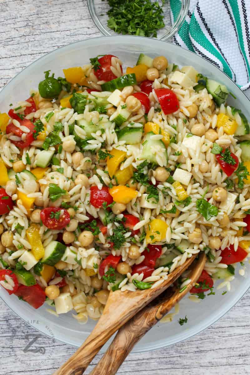 Orzo Pasta Salad in a bowl with wooden spoons