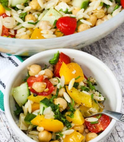 Orzo Pasta Salad in a white bowl with a spoon