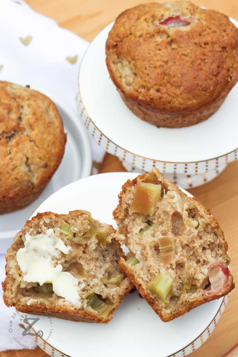 Sourdough Rhubarb Muffins with one on a platter in half with butter