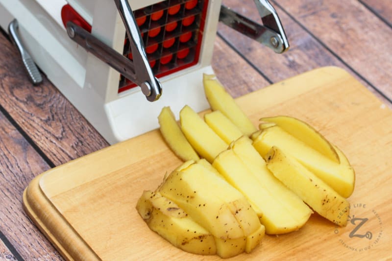 cutting potatoes with a slicer to make Oven Baked Fries