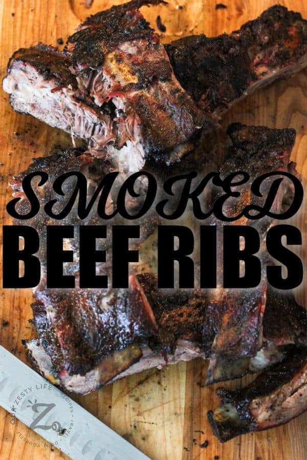 Smoked Beef Ribs cut up on a wooden board with a title