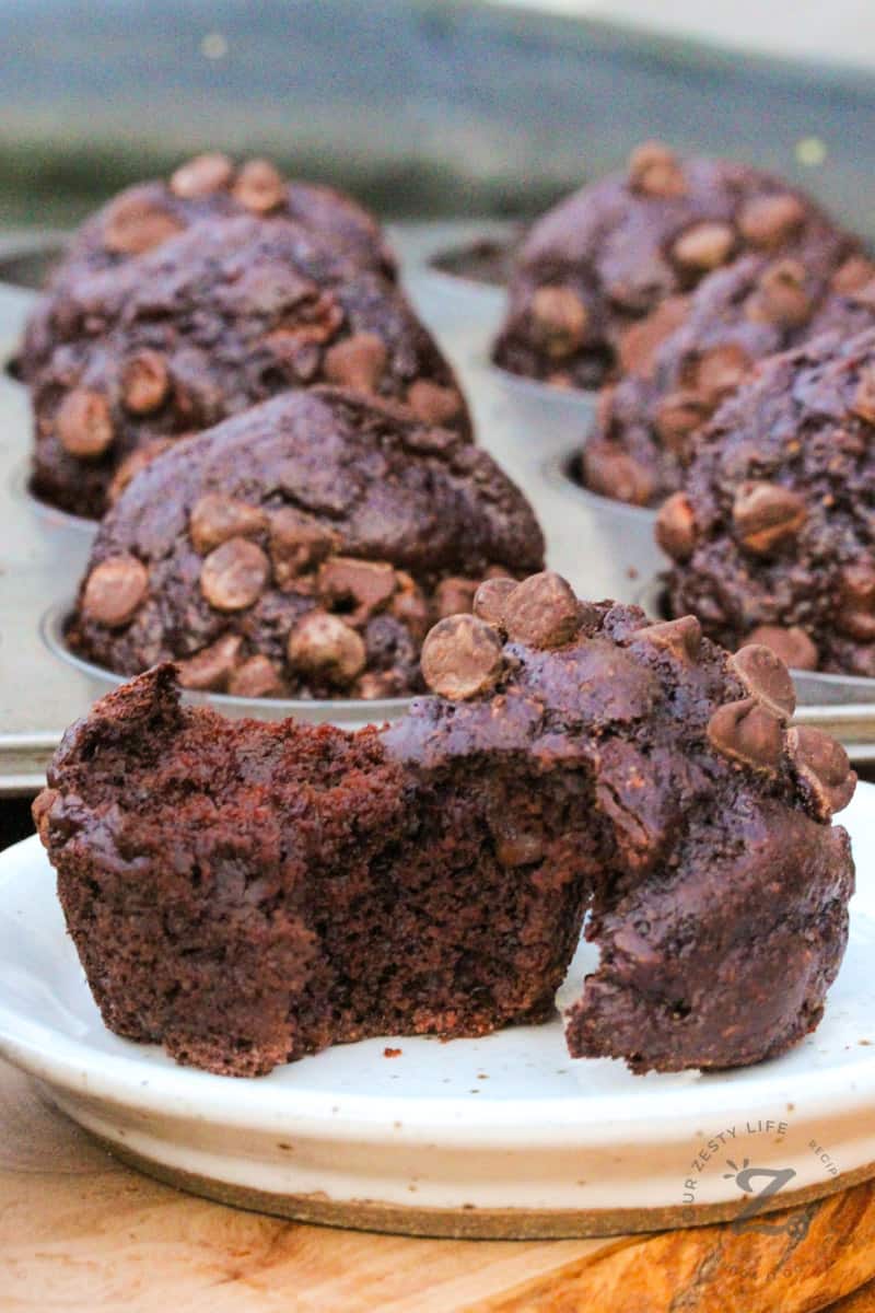Chocolate Zucchini Muffins with one cut open on a plate