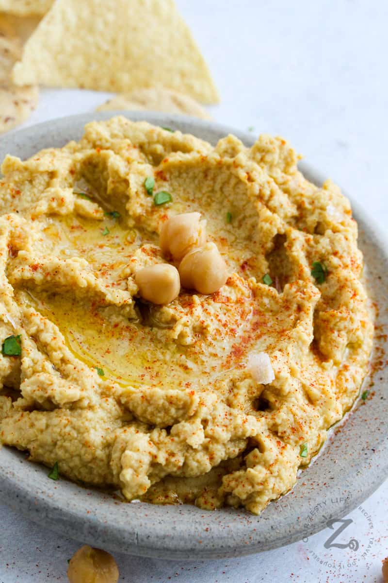 close up of Hummus on a platter with chips in the back