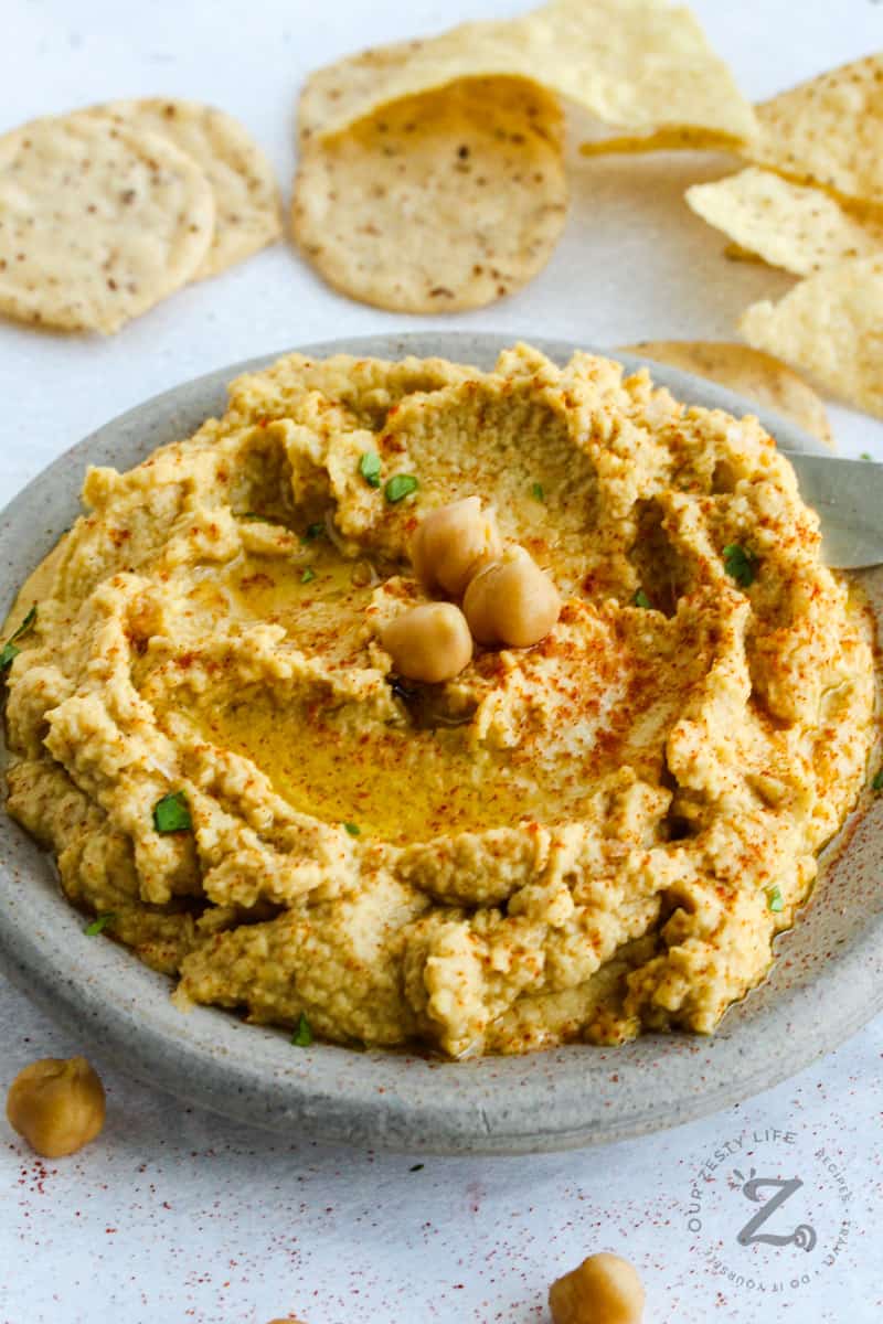 Hummus on a platter with chips in the background