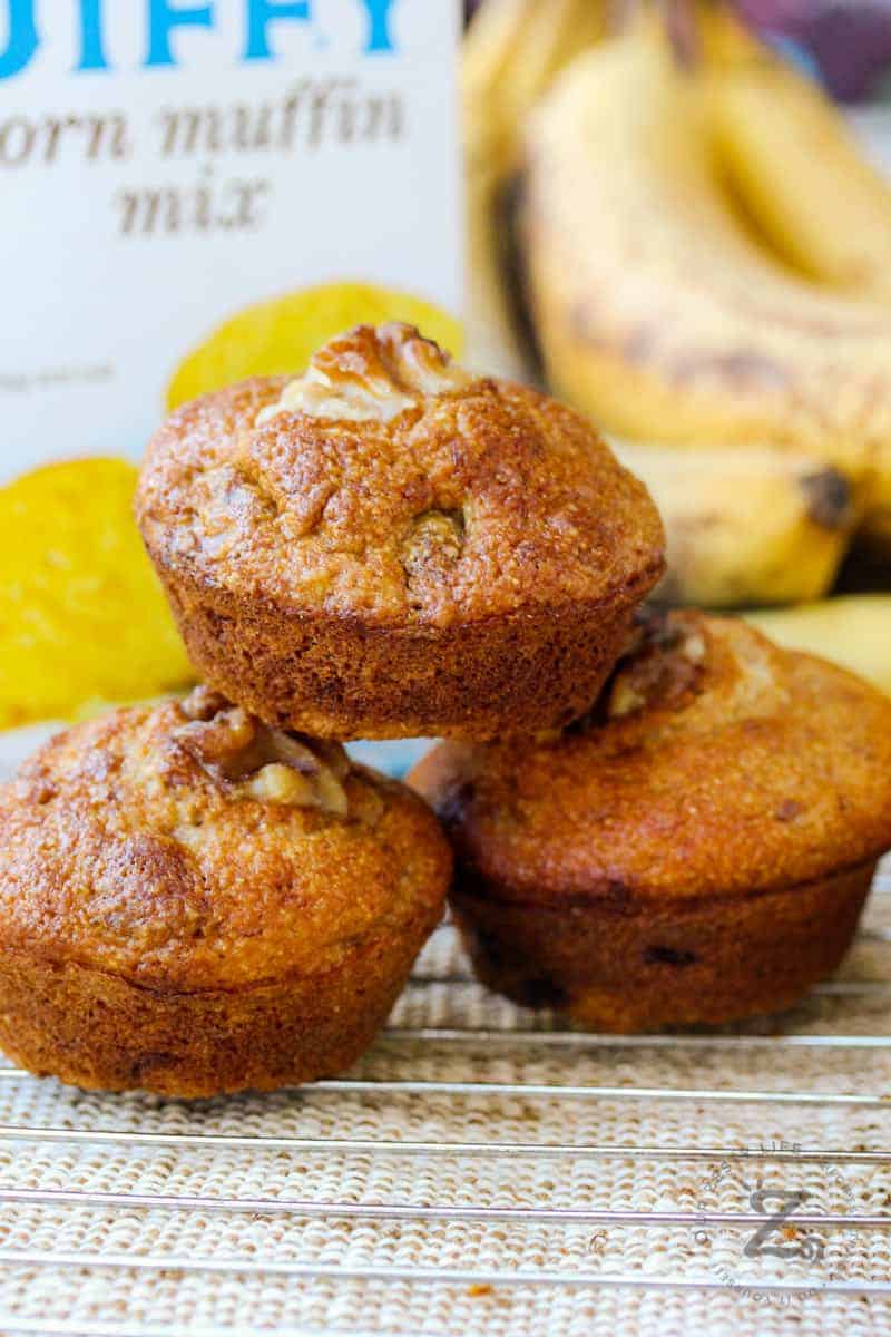 three muffins stacked on eachother with juffy box in the back to make Banana Corn Muffins
