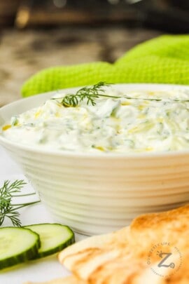 Tzatziki in a bowl with cucumber and pita beside it