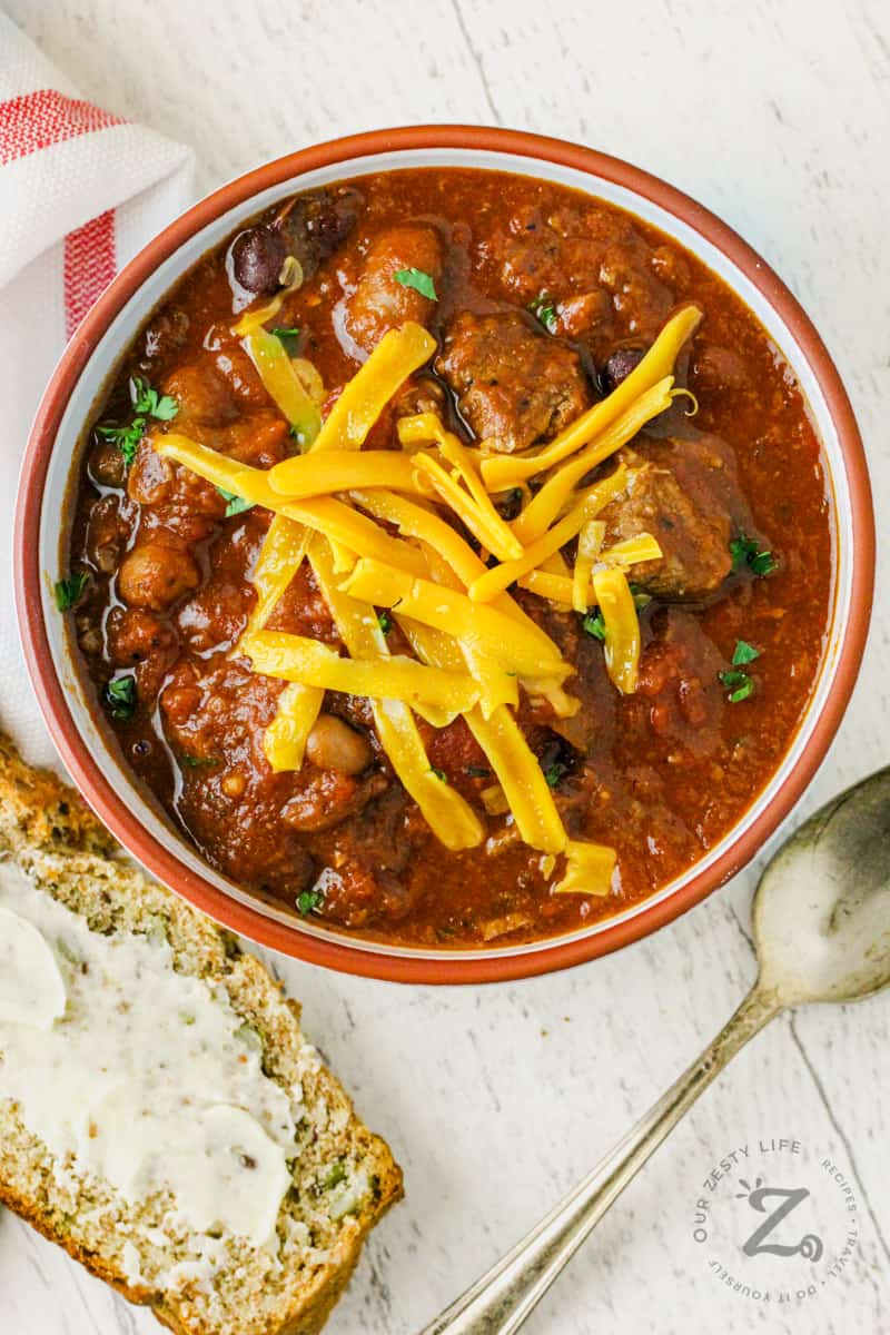 bowl of Chili with Stew Meat with spoon and buttered bread beside it