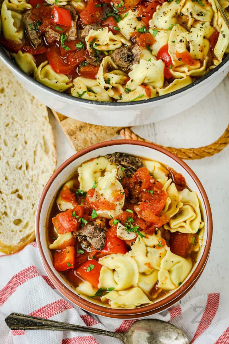 Tortellini Soup in a bowl with bread and spoon