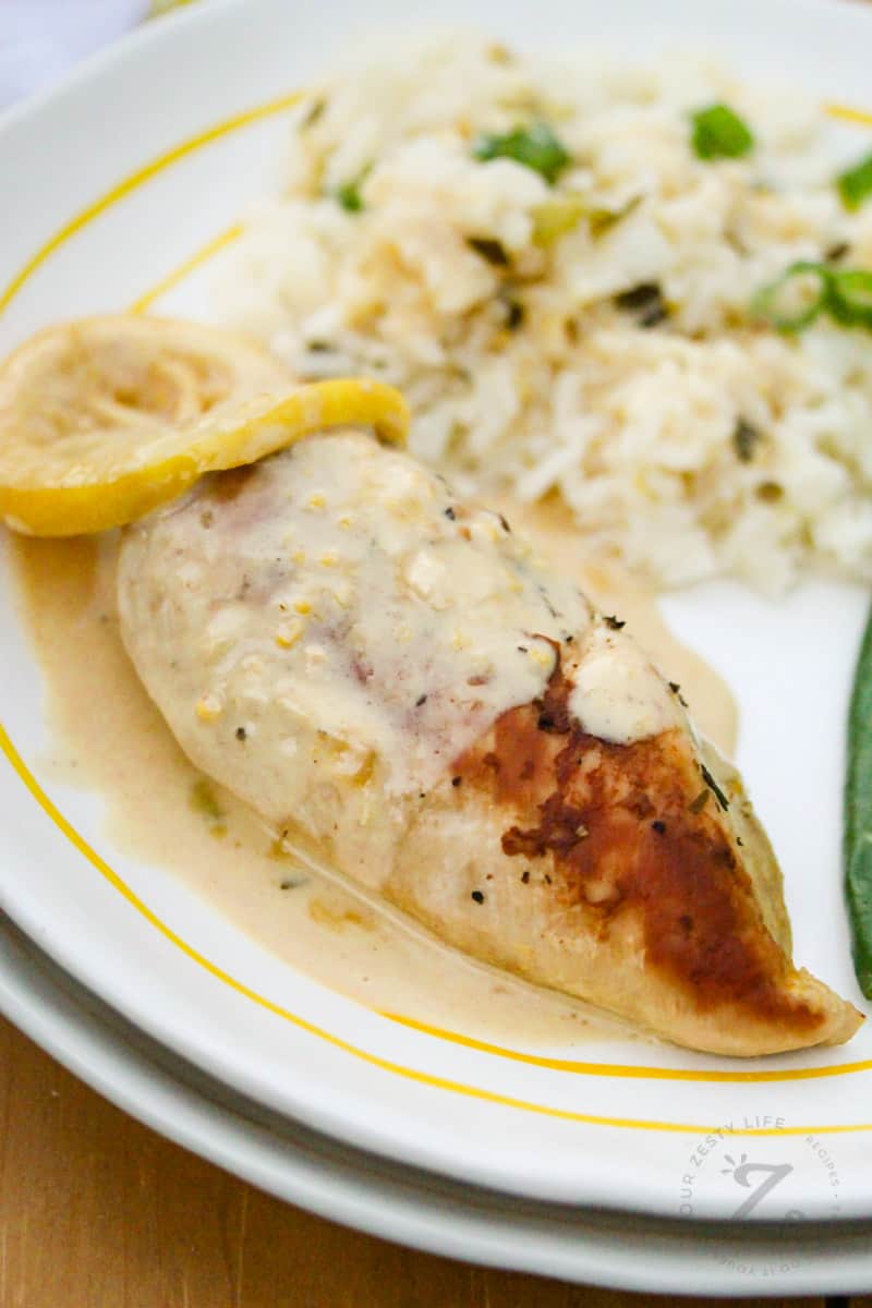 cooked Creamy Lemon Chicken on a plate with a lemon